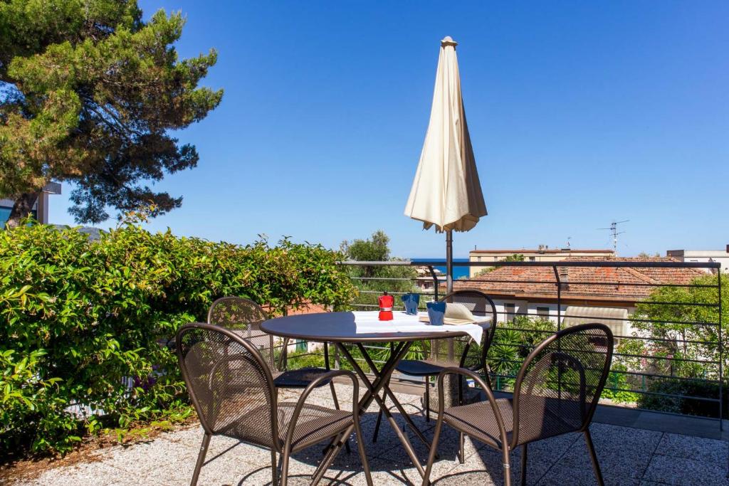 einen Tisch mit Stühlen und einem Sonnenschirm auf dem Balkon in der Unterkunft Appartamento Verdemare in Diano Marina