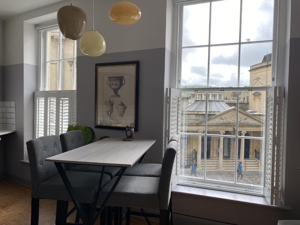 a dining room with a table and chairs and a window at Roman Bath View in Bath