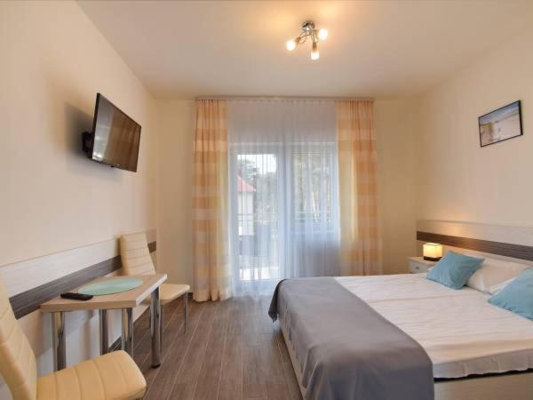 a bedroom with a bed and a desk and a television at Dorato24 in Mrzeżyno