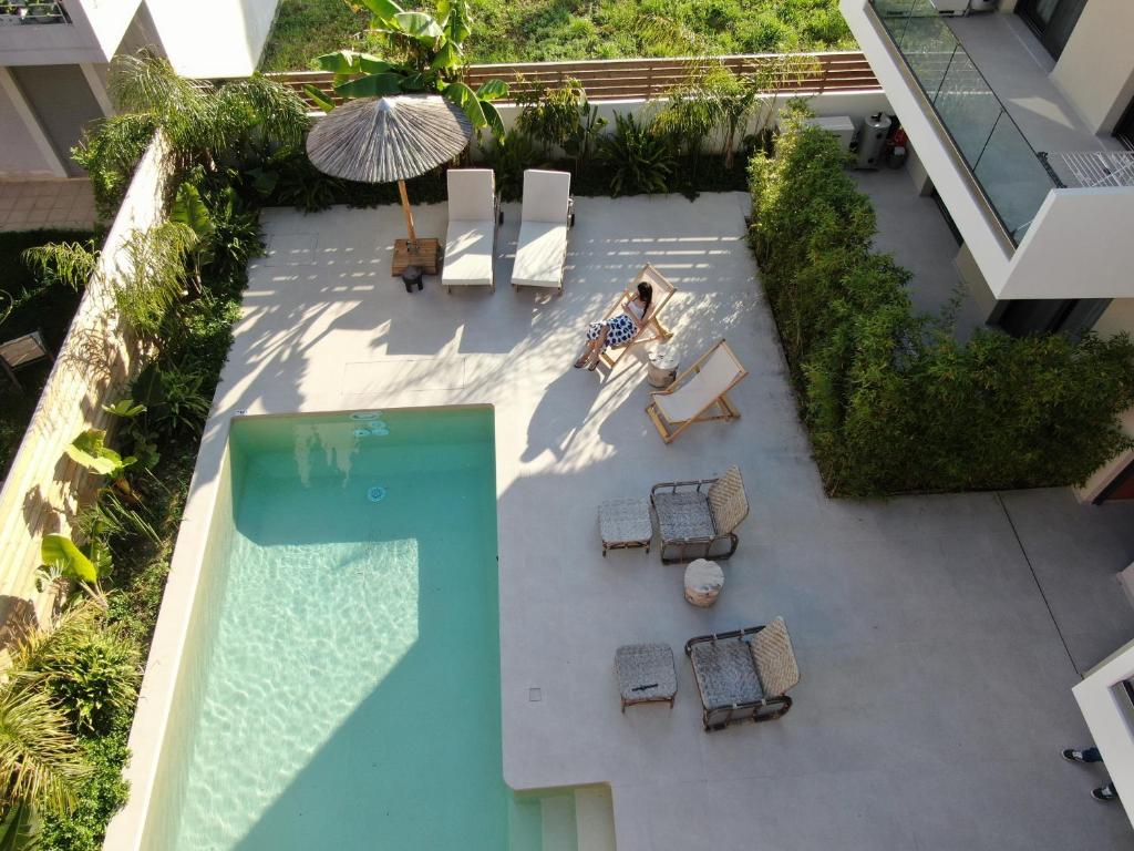 una vista aérea de una piscina con sillas y sombrilla en Pnoe - Feel at Home, en Lefkada