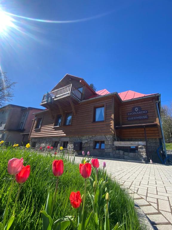 a wooden building with red tulips in front of it at Leonardo Guesthouse in Świeradów-Zdrój