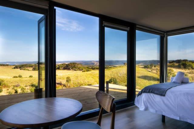a bedroom with a bed and a table and some windows at Sky Ship 1 - Luxury Off-Grid Eco Accommodation in Cape Otway