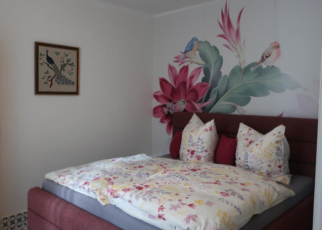 1 dormitorio con 1 cama con una pintura floral en la pared en Müllers Wellness Ferienhaus, en Döbrököz
