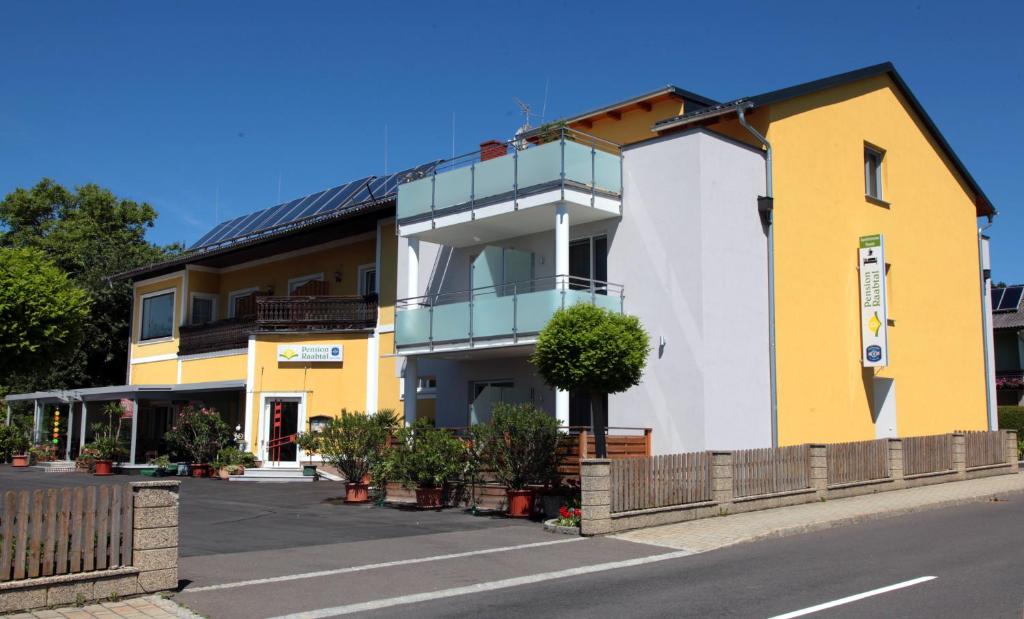 un bâtiment jaune et blanc sur le côté d'une rue dans l'établissement Hotel & Frühstückspension Raabtal, à Feldbach