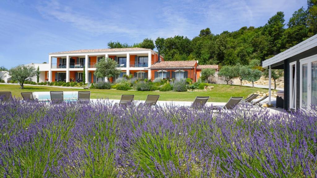 une maison avec des chaises et un champ de fleurs violettes dans l'établissement Le Mas des Oliviers, à Gréoux-les-Bains