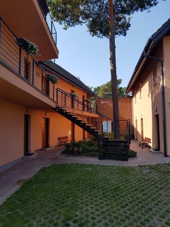 a courtyard of a building with a staircase and a tree at Relax in Niechorze