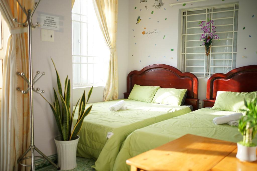 Jaymo Motel في فنغ تاو: سريرين في غرفة نوم مع شراشف خضراء وطاولة