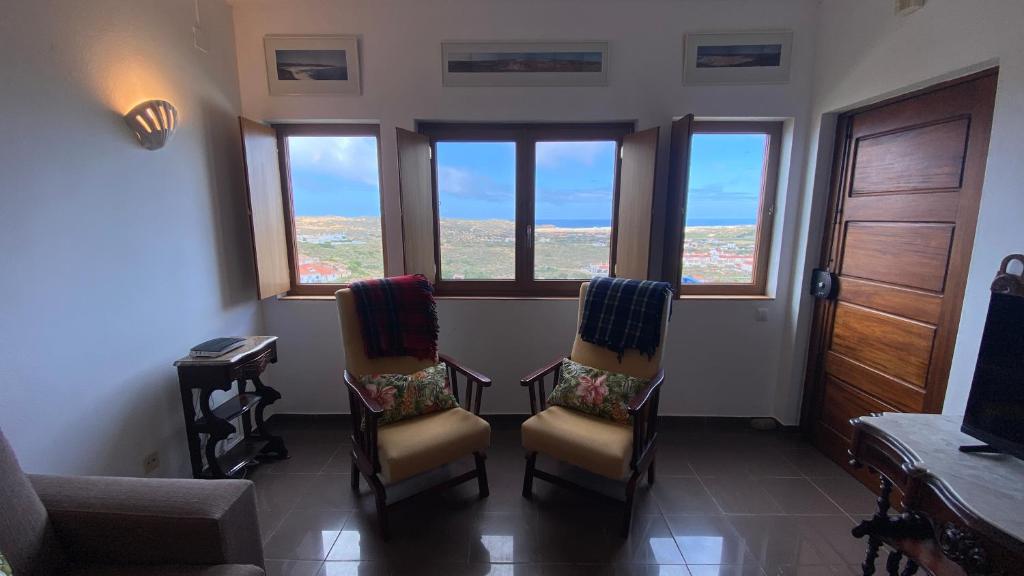 een kamer met 2 stoelen, een tafel en ramen bij Casa do Miradouro in Carrapateira