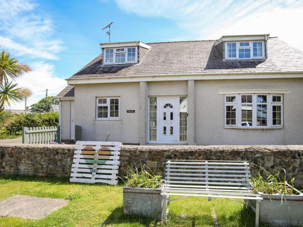 a white house with a bench in front of it at Homely 4-Bed House close to stunning beach in Pwllheli
