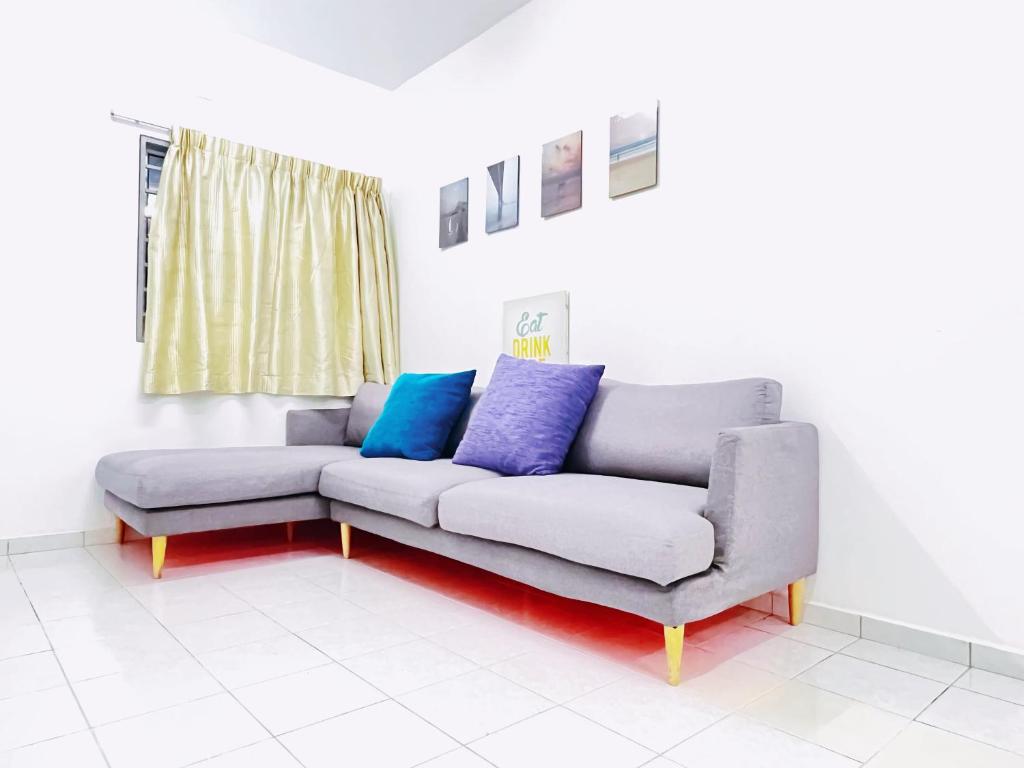 a couch in a living room with blue and purple pillows at Simply Cosy Homestay in Batu Caves