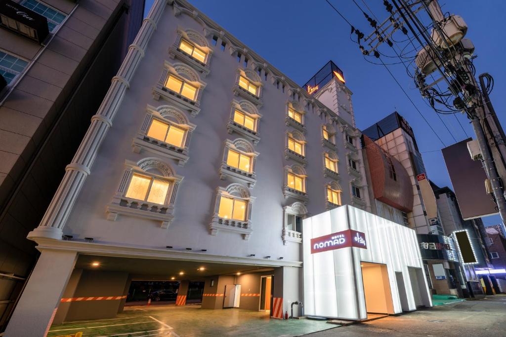 a large building with lit windows on a city street at The Hyoosik Nomad Aank Hotel Gumi in Gumi