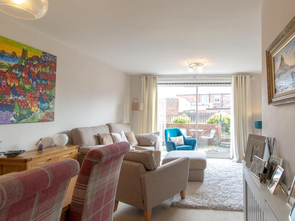 ein Wohnzimmer mit einem Sofa, Stühlen und einem Fenster in der Unterkunft Pass the Keys Cosy Seaside Home with Free Parking in North Shields