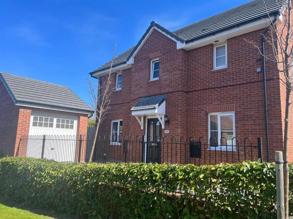 a red brick house with a black fence at Remarkable 3-Bed House in Wirral in Wirral