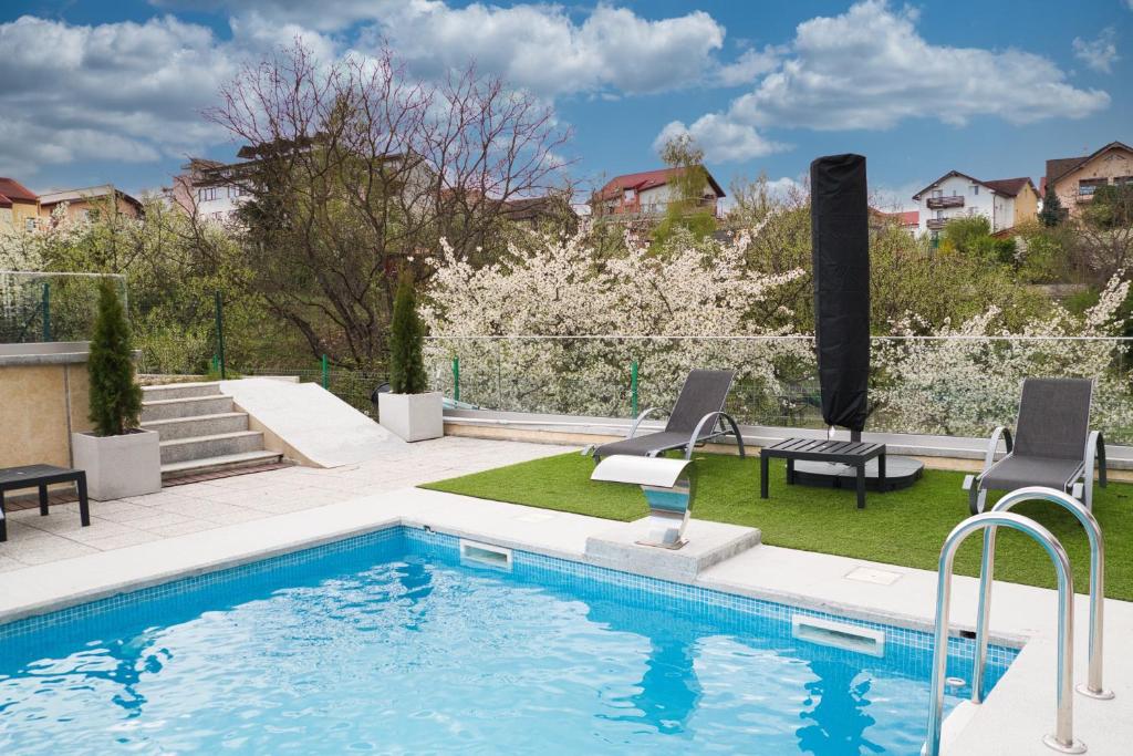 una piscina con 2 sillas junto a un patio en Panorama Deluxe Aparthotel, en Cluj-Napoca