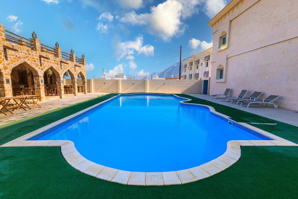 a large pool with blue water in a courtyard at Esra Hotel Apartment in Khasab