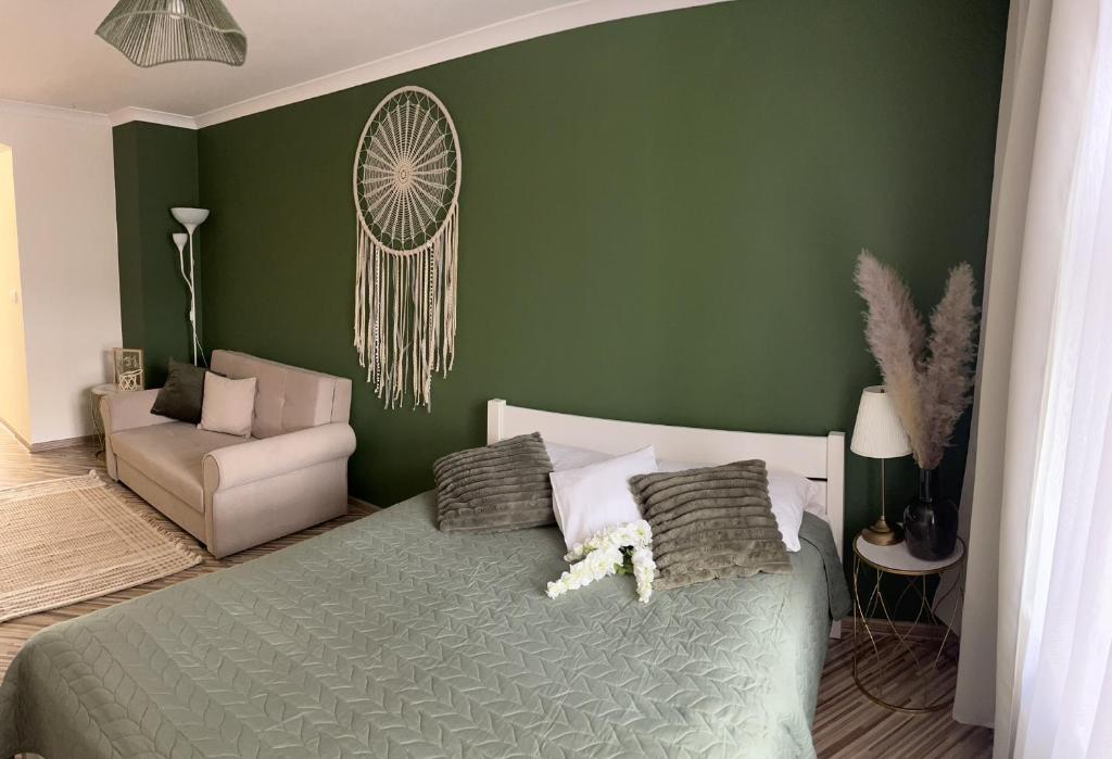 Apartament na Starówce Boho في بيشتنا: غرفة نوم خضراء بسرير وكرسي