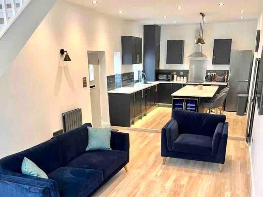 a living room with a couch and a kitchen at Stunning modern 2 bedroom, 2 bathroom townhouse in Cheltenham