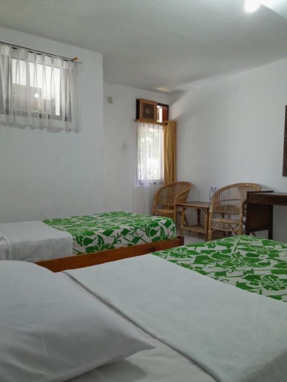 Hotel Pison في رانتيباو: غرفة نوم بسريرين وطاولة وكراسي