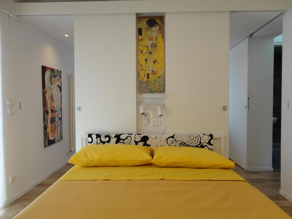 een slaapkamer met een bed met een gele deken bij CASA KLIMT vicinissima al mare parcheggio privato gratuito se disponibile in Pescara