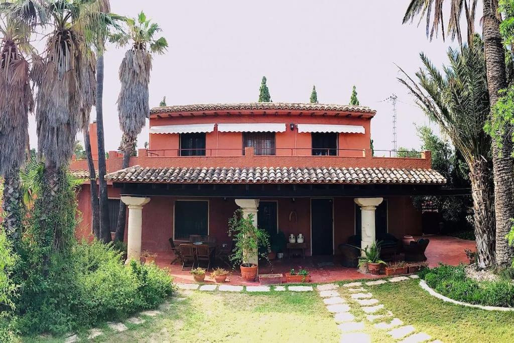 uma casa vermelha com palmeiras em frente em Magnifica Villa Vacacional en entorno rural em Alicante