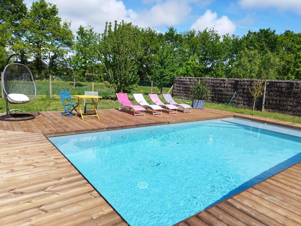 einen Pool auf einer Holzterrasse mit Stühlen und einem Tisch in der Unterkunft Chambre d'hôtes salle d'eau et WC privés, véranda,extérieurs et piscine chauffée in Guérande