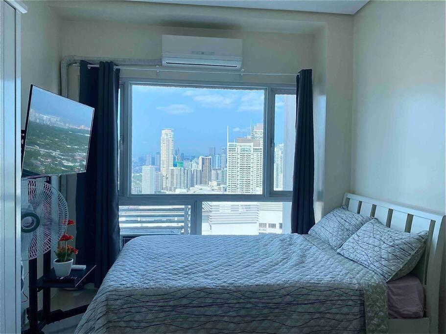 a bedroom with a bed and a large window at Makati Penthouse with Stunning City Skyline View in Manila