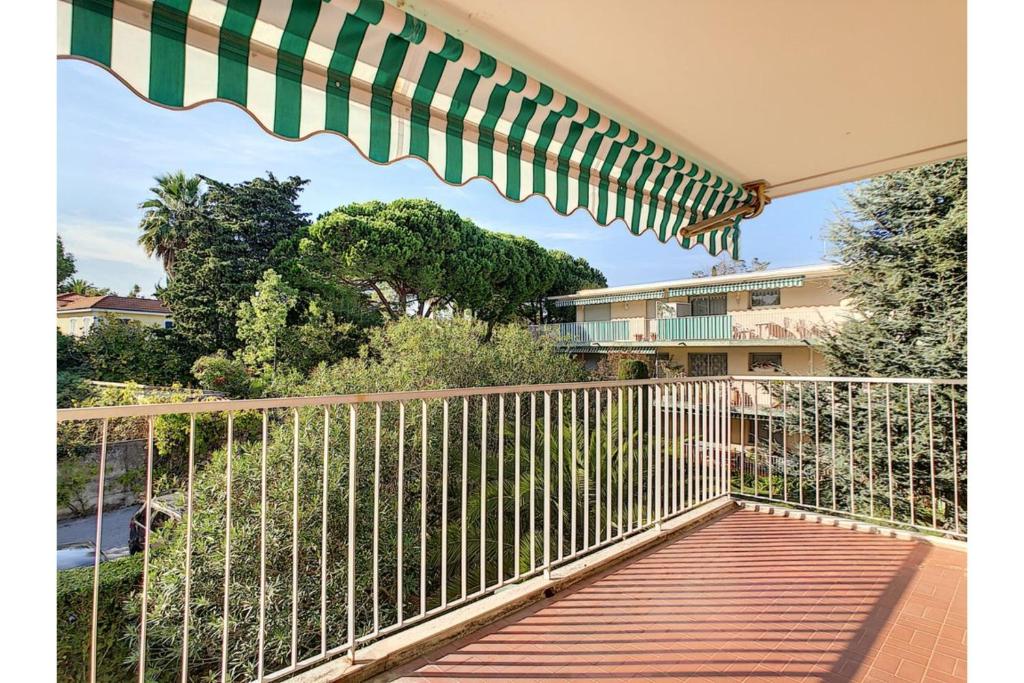 einen Balkon mit einem grünen und weißen Regenschirm auf einer Brücke in der Unterkunft L'Ermitage - Happy Rentals in Antibes