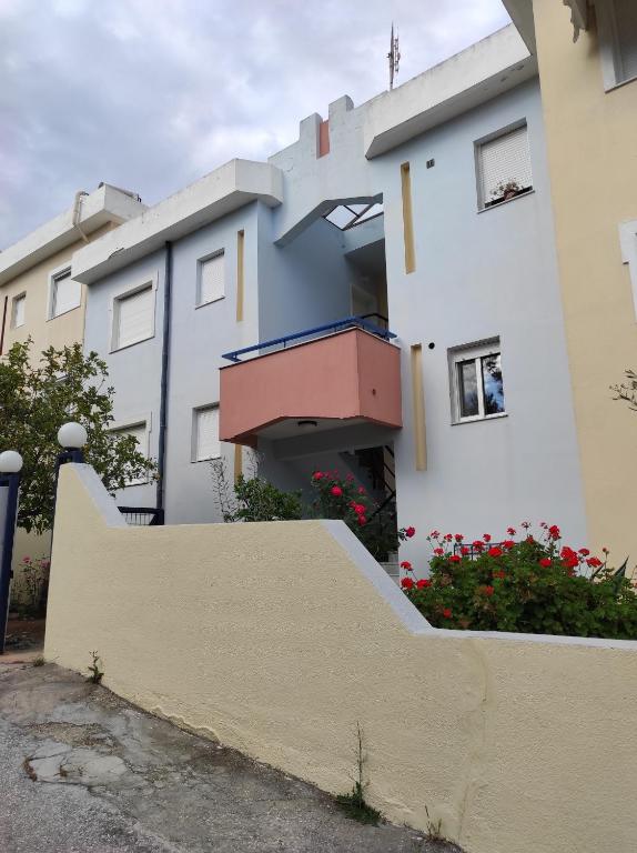 a row of houses with a fence and flowers at Theodora's Bay View Apartment in Nea Peramos