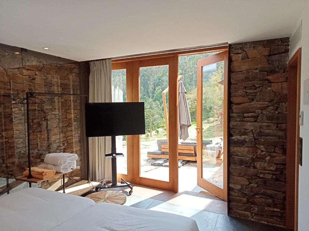 a bedroom with a bed and a stone wall at Moinhos do Paiva in Castelo de Paiva