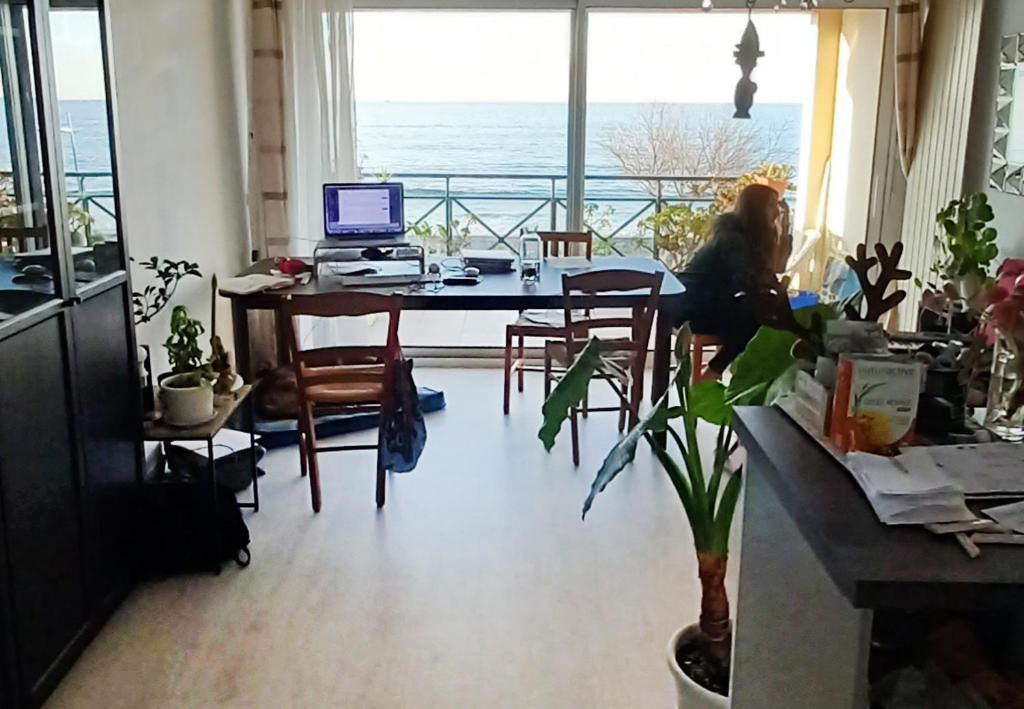 una mujer sentada en una mesa con un ordenador en una habitación en Appartement bord de mer très lumineux 2/4 pers. - Vue inoubliable en Hendaye