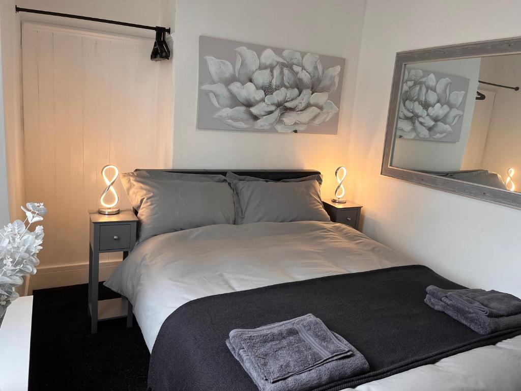 a bedroom with a bed with two lamps and a mirror at Sandy Toes : Relaxing Contemporary Victorian Apartment 10 mins to Beach in Torquay