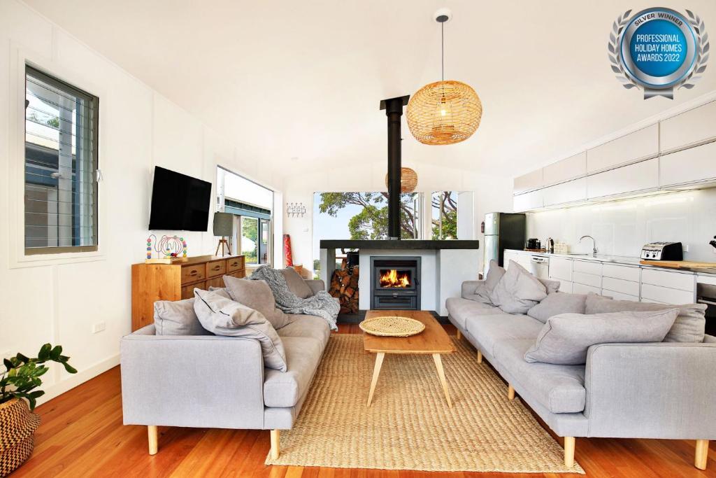 - un salon avec deux canapés et une cheminée dans l'établissement Ayana - Pet Friendly - Directly Opposite Beach - Fireplace, à Currarong