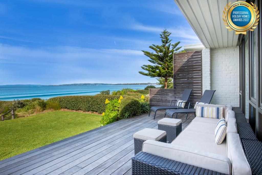 a deck with a couch and chairs on a house at Azure Absolute Beachfront I Pet Friendly in Callala Beach