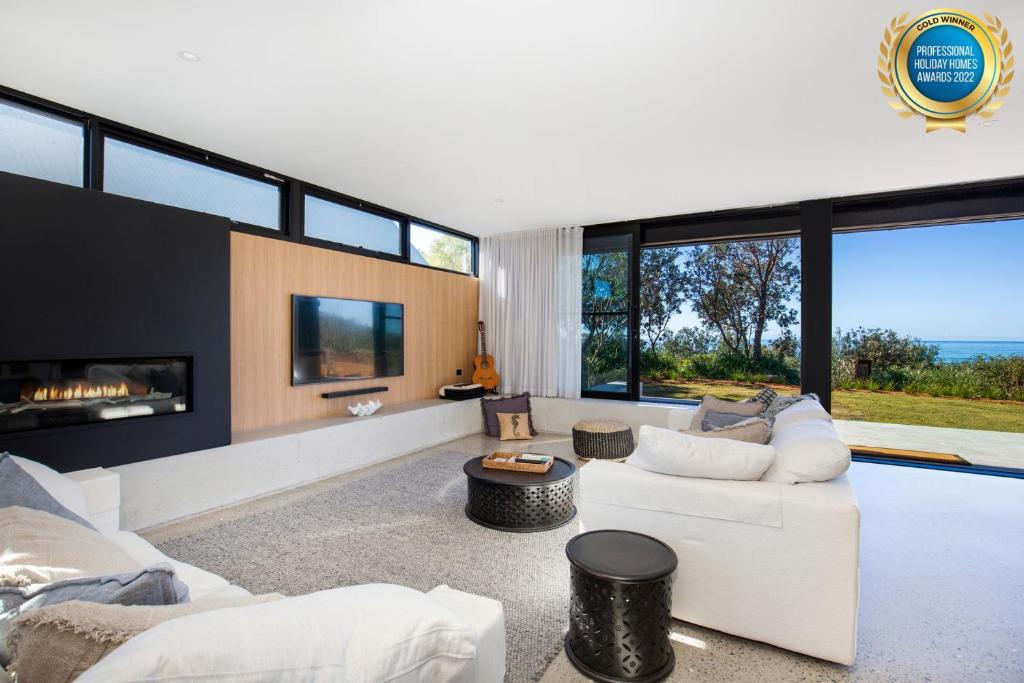 uma sala de estar com mobiliário branco e janelas grandes em Banksia I Absolute Beachfront em Culburra Beach