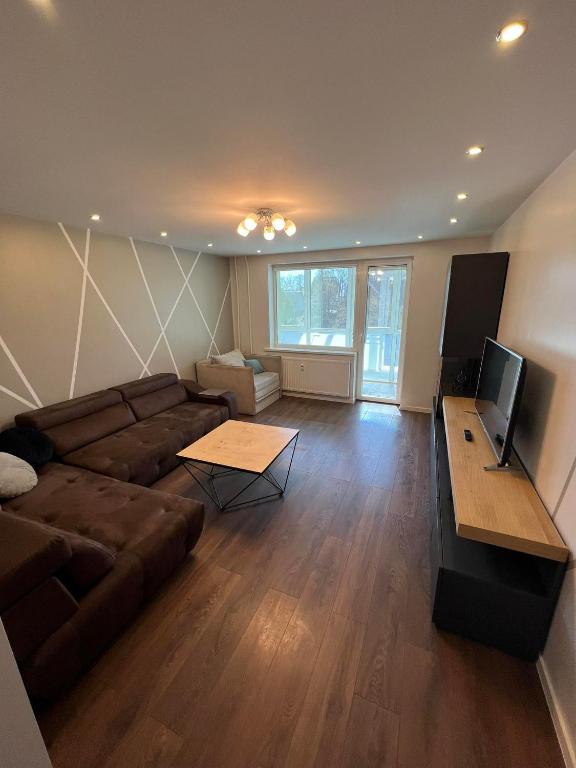 a living room with a couch and a flat screen tv at LUNA Apartamentai in Akmenė