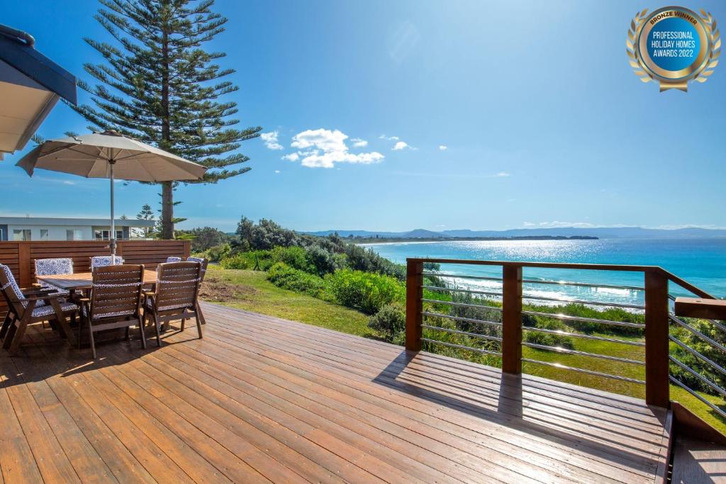 a wooden deck with a table and chairs and the ocean at Eclipse Absolute Beachfront with Stunning Views in Culburra Beach