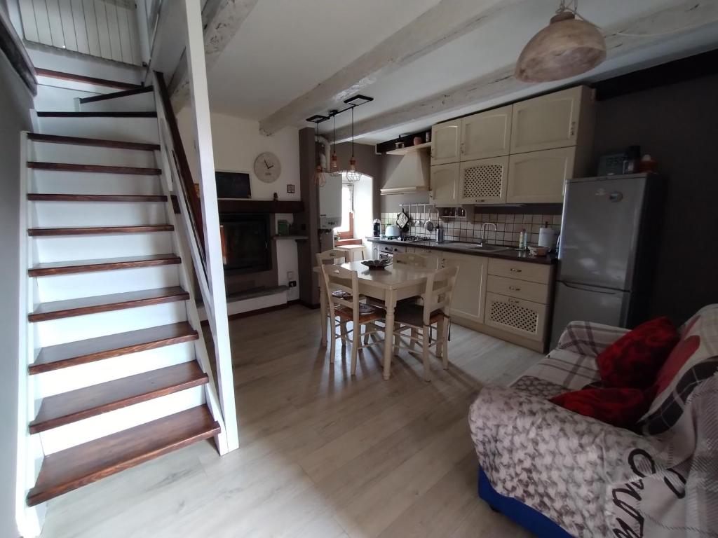 sala de estar con escalera, mesa y cocina en La Ghianda con terrazza, en Cossogno