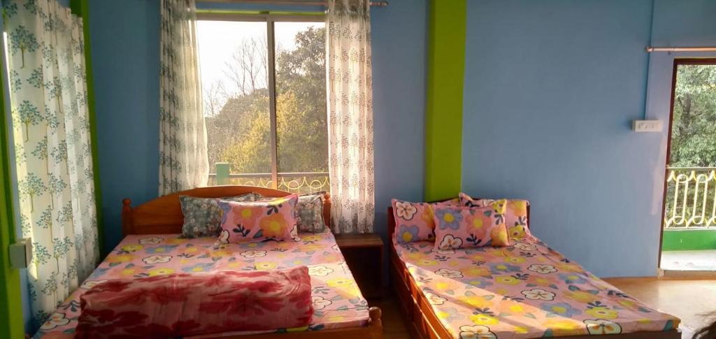 a bedroom with two beds and a window at Greenery Homestay in Darjeeling