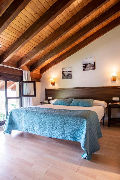 a bedroom with two beds in a room with wooden ceilings at Apartamentos Aldea del Puente in Cangas de Onís