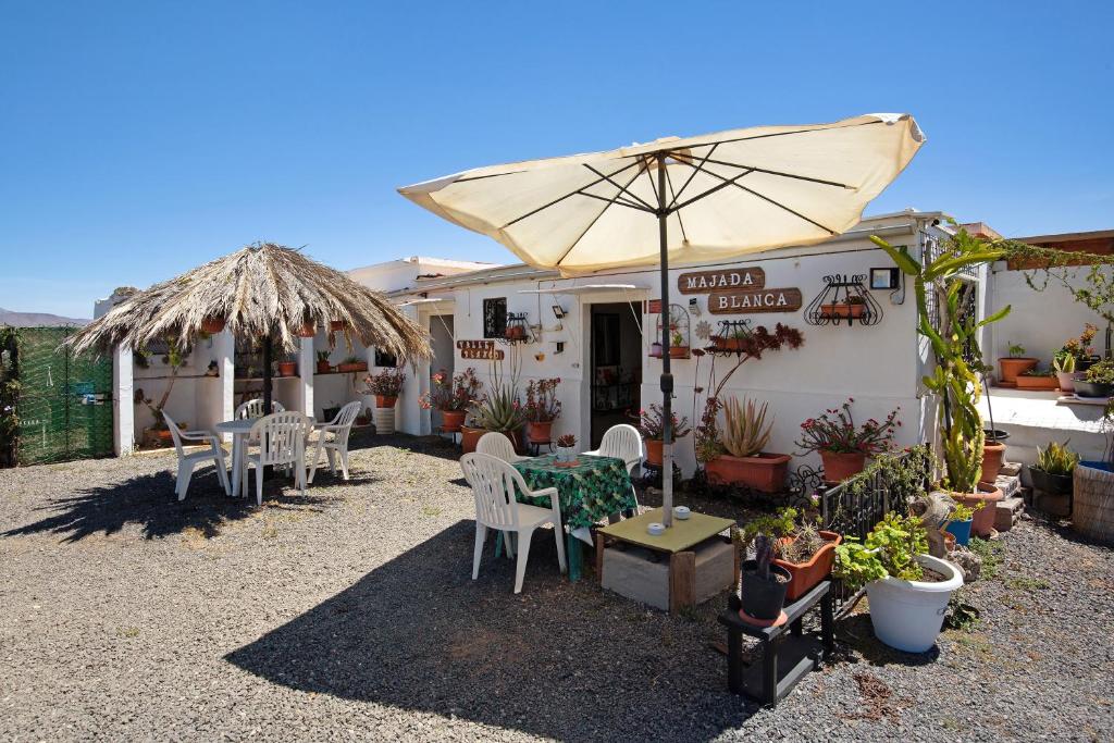 um restaurante com mesas e cadeiras e um guarda-sol em Majada Blanca em Valles de Ortega
