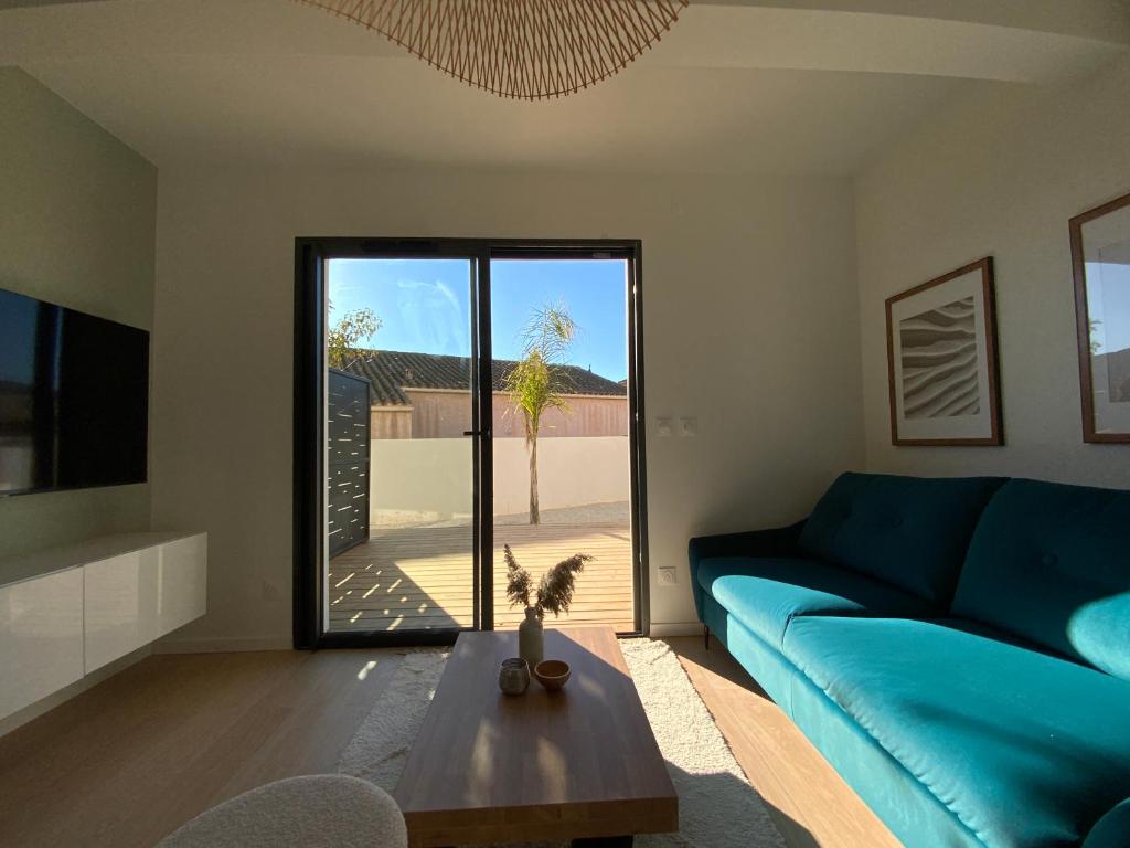 a living room with a blue couch and a table at Les Loges de la Mer - Pérols in Pérols