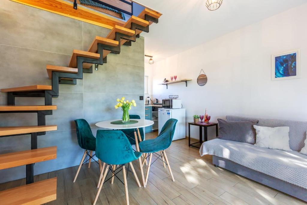 a living room with a table and chairs and a staircase at Loft House Rozewie in Jastrzębia Góra