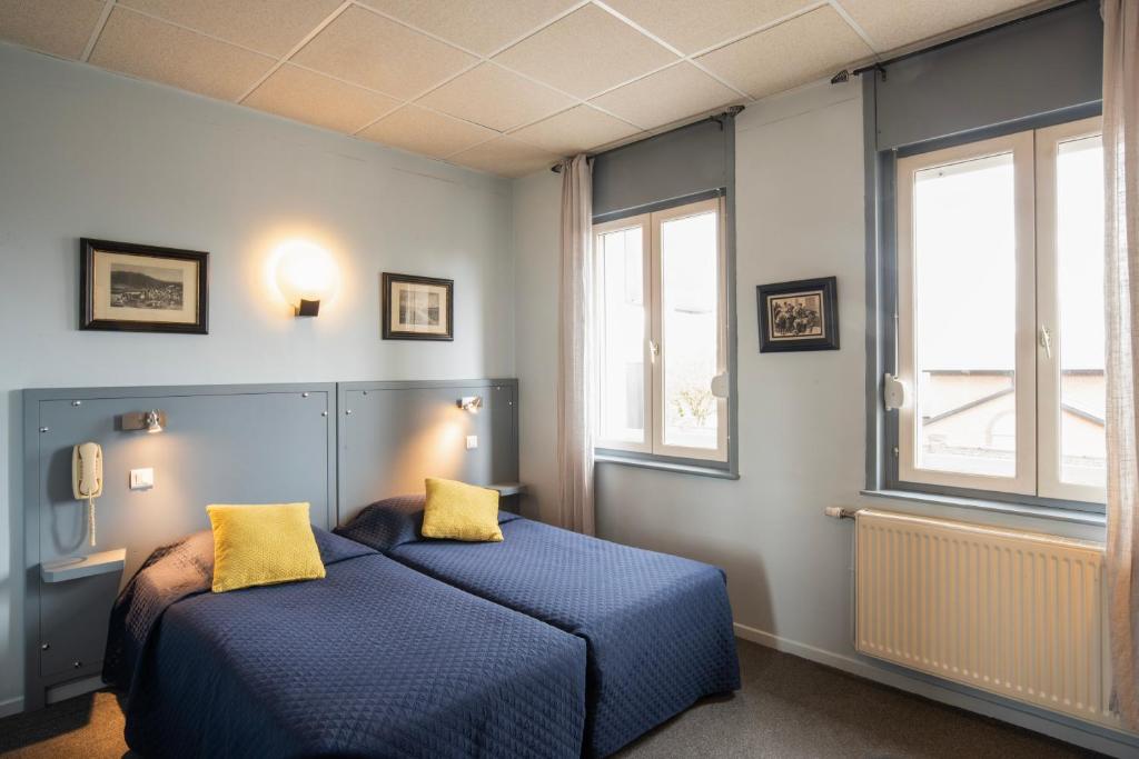 2 camas en una habitación con 2 ventanas en Hotel La Chope, en Cambrai