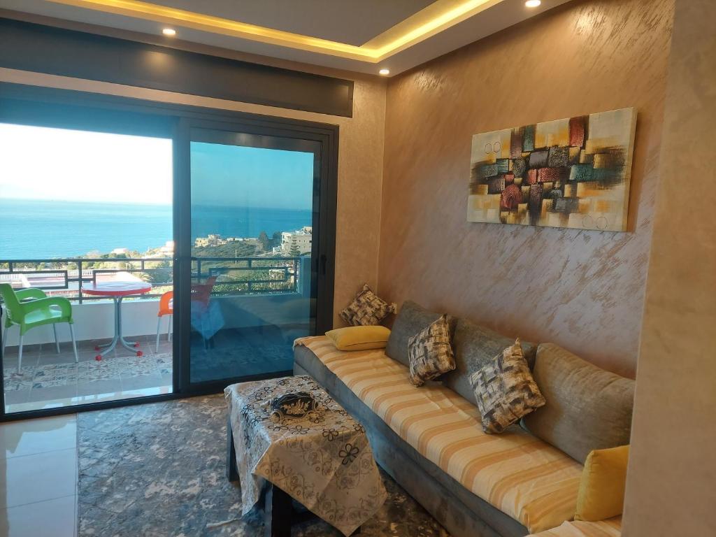 a living room with a couch and a view of the ocean at Blue Horizon-Ghougine in Tangier