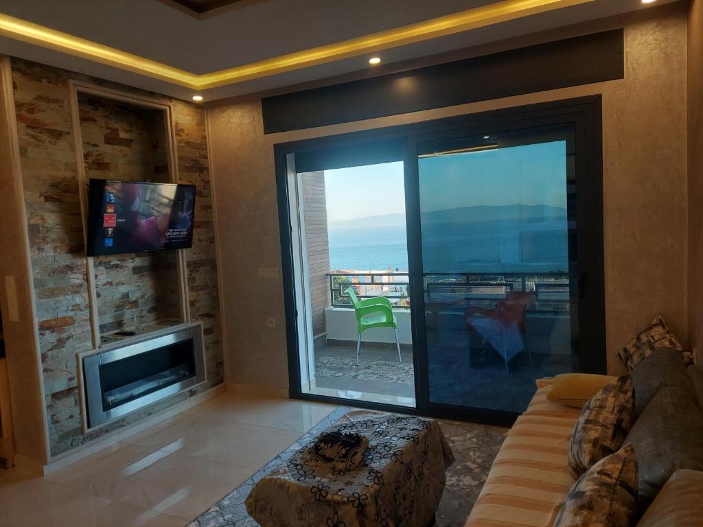 a living room with a large glass door with a tv at Blue Horizon-Ghougine in Tangier