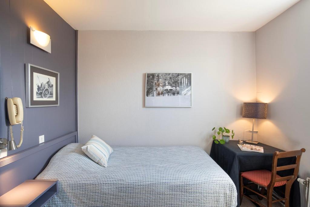 a bedroom with a bed and a desk with a phone at Hotel La Chope in Cambrai