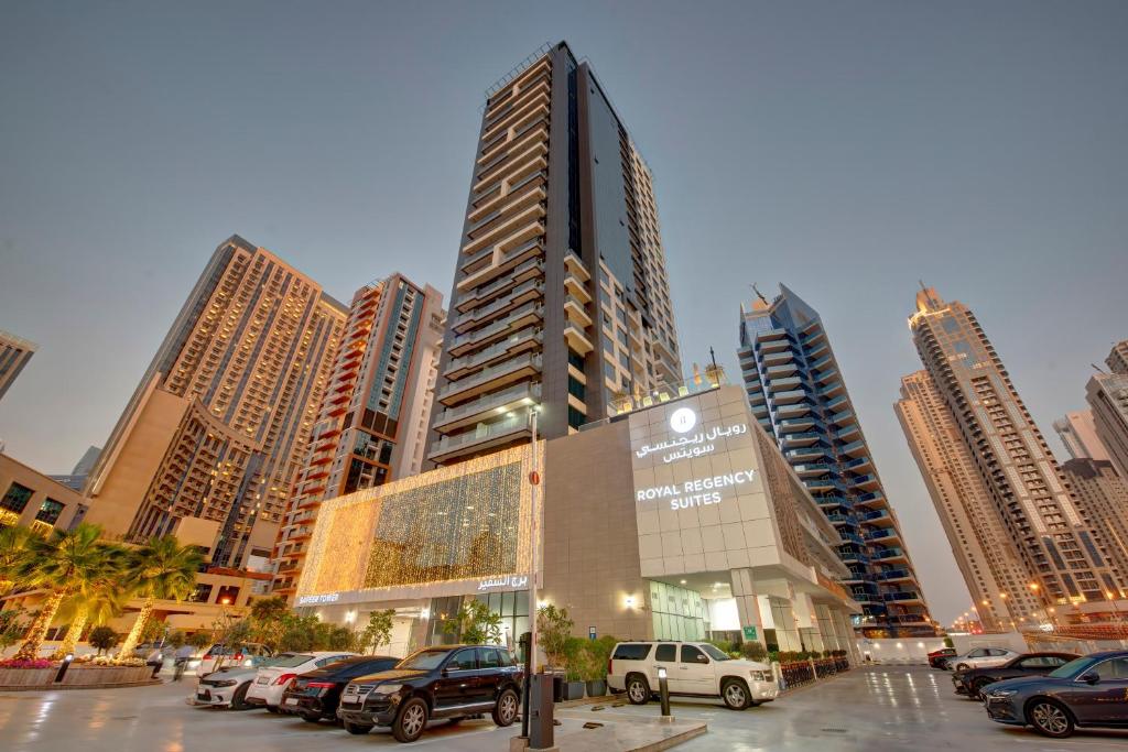 a tall building with cars parked in a parking lot at Royal Regency Suites Marina in Dubai