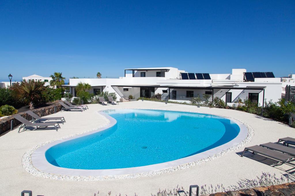 a swimming pool with chairs and a house in the background at Mana EcoRetreat in Las Breñas