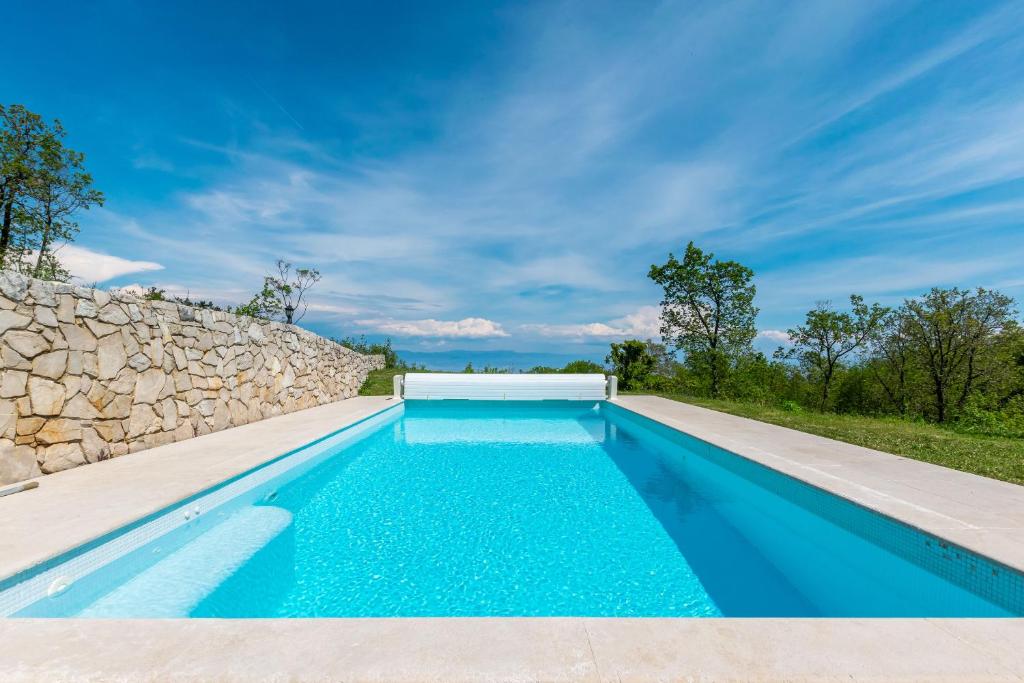 una piscina frente a un muro de piedra en House Rada i Stanisav, en Mošćenička Draga