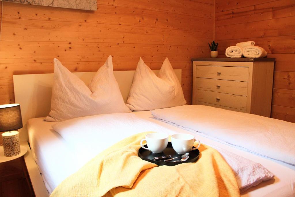 a bed with two cups and a tray on it at Das Paradieschen in Edlitz